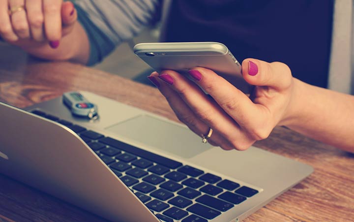 woman making calculations on phone and computer